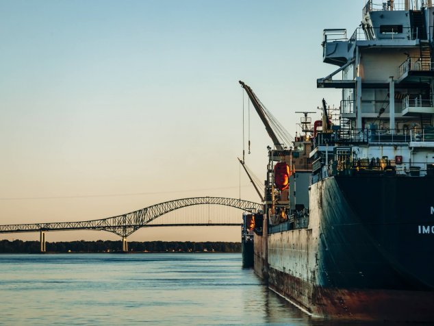 Un navire-cargo accoste au port de Trois-Rivières, avec le pont Laviolette en arrière-plan surplombant le fleuve Saint-Laurent.