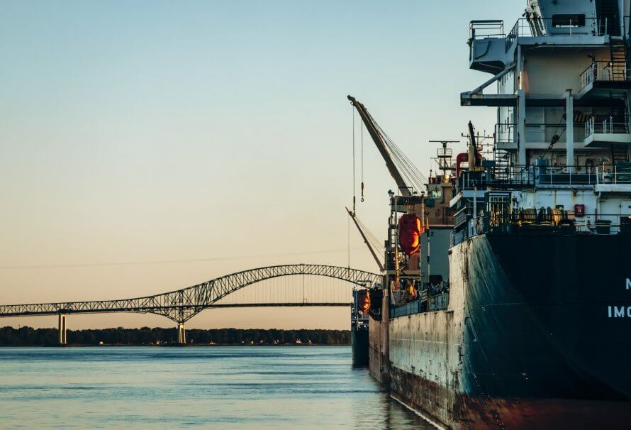 Un navire-cargo accoste au port de Trois-Rivières, avec le pont Laviolette en arrière-plan surplombant le fleuve Saint-Laurent.