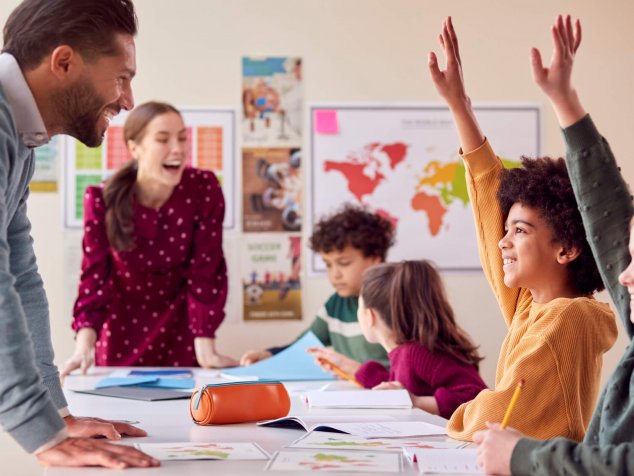 Groupe d’élèves multiculturels avec des enseignants en classe qui lèvent la main pour répondre à la question.