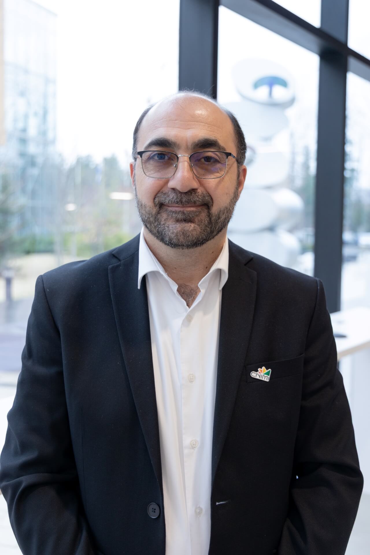 Photo professionnelle d'Hussein Ibrahim, directeur du CNIMI, prise devant les fenêtres du centre.