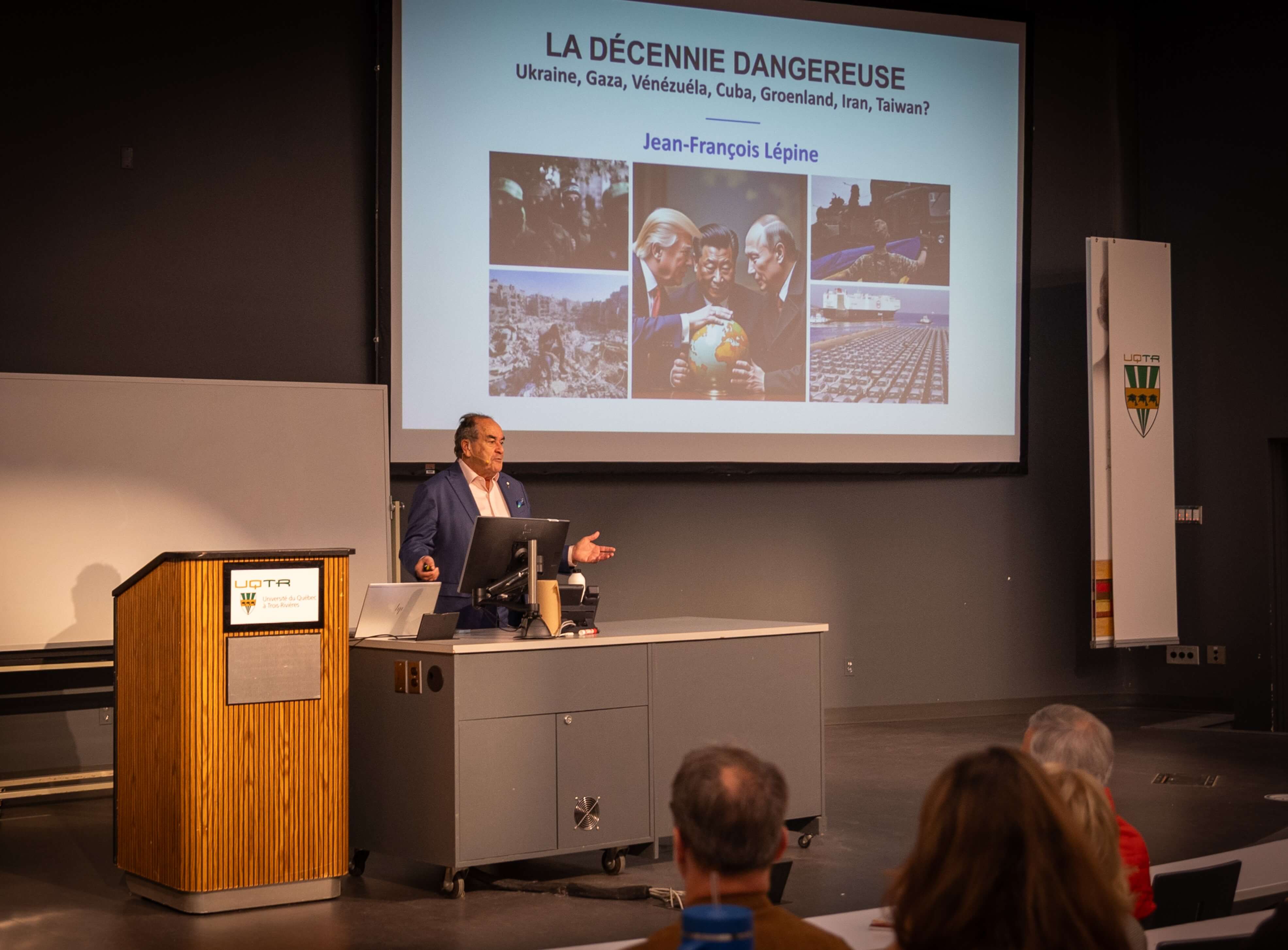 Jean-François Lépine se tient à l'avant d'un auditorium, et présente la première diapositive de sa conférence.